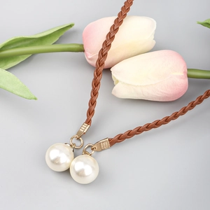 Detail of bohemian brown braided waist rope featuring gold metal tips and white pearls