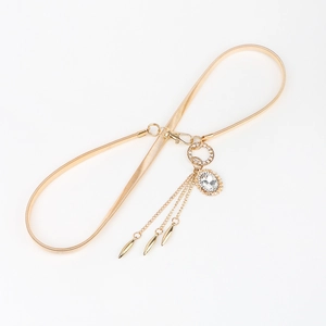 Detail of gold metal snake chain belt featuring oval rhinestone buckle and chain tassels