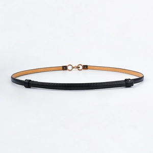 Detailed close-up of a thin black leather belt with a golden interlocking buckle design