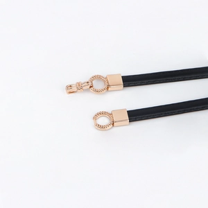 Detail of slim black leather belt with gold circular alloy buckle for fashion dresses