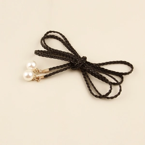 Detailed macro view of woven black waist rope belt featuring elegant round white pearls