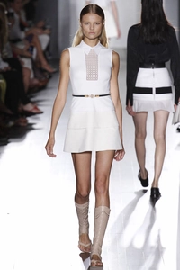 Detailed view of elegant pearl belt cinching a white layered dress on a runway
