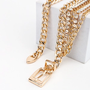 Détail de la ceinture chaîne dorée multicouche avec strass et pendentif en cœur