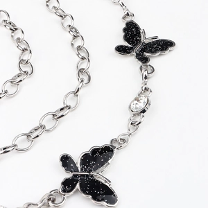 Detail of silver chain belt featuring black glittery butterflies and a sparkling rhinestone