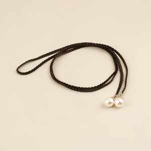 Detail of bohemian waist rope with black braided cord and elegant white pearl pendants