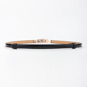 Détail d'une fine ceinture en cuir noir avec boucle dorée ajourée pour robe