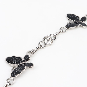 Detail of silver chain with black glitter butterfly pendant and sparkling clear rhinestone
