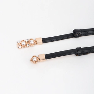 Détail de la boucle de ceinture dorée avec perles et strass sur bracelet en cuir noir fin