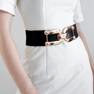 Detail of black elastic waist belt with gold U-shaped buckle on a white dress