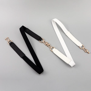 Dettaglio di cinture elastiche bianche e nere con eleganti fibbie in metallo dorato
