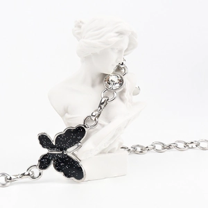 Detailed close-up of a silver chain belt featuring a black glitter butterfly and large crystal