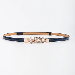 Détail de la ceinture fine bleu foncé avec boucle fleur en perles dorées et strass