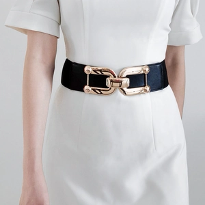 Detail of wide elastic black waist belt with polished gold interlocking metal buckle