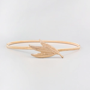 Detailed macro view of the three-leaf metal buckle on a polished gold elastic waist chain