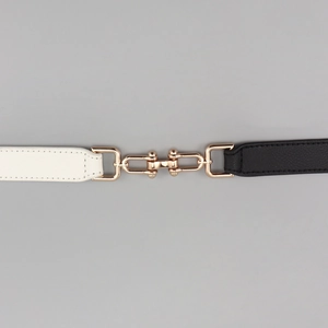 Dettaglio di una cintura in pelle bicolore bianco e nero con fibbia in metallo dorato