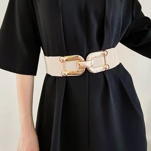 Detailed macro view of the polished gold-tone metal clasp on a wide off-white elastic belt