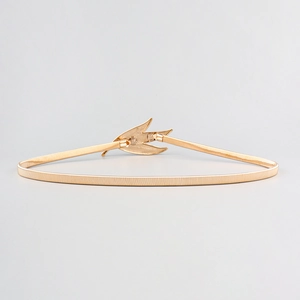 Detailed close-up of golden metal leaf buckle with elastic spring chain for dresses