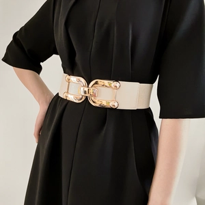Detail of a beige elastic cinch belt featuring a large gold-tone double ring metal buckle