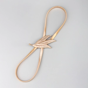 Detail of golden metallic elastic waist chain with three-leaf buckle for dresses