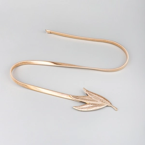 Detailed macro view of the gold metallic leaf buckle and elastic spring waist belt