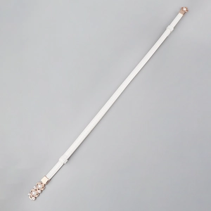 Détail de ceinture blanche montrant une boucle fleur or rose avec perles et strass