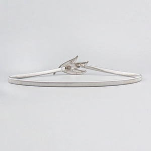 Detail view of the silver leaf-shaped alloy buckle on the metallic elastic waist belt