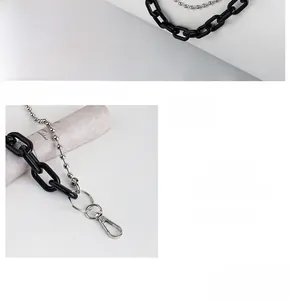 Detail of punk style silver ball chain and black resin links with rotating clasp