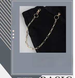 Detail of a hip-hop style golden hollow chain with metal spring carabiners on black trousers