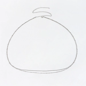 Chaîne de corps minimaliste argentée à double couche avec fermoir mousqueton sur fond blanc