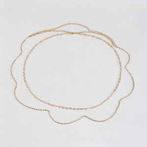 Macro shot of double-layer gold waist chain with heart-shaped links and lobster clasp