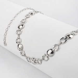 Dettaglio della catena da corpo in argento con maglie geometriche e piastre metalliche lucide