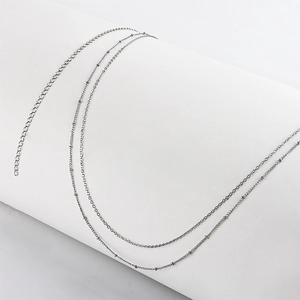 Détail de la double chaîne argentée avec perles métalliques et extension ajustable