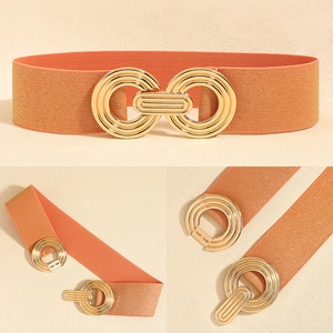 Detail of orange elastic waist belt featuring a textured golden interlocking circular buckle