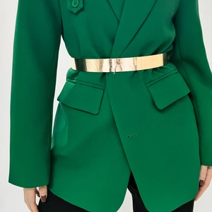 Close-up of golden metal waist belt with embossed patterns on a green suit jacket