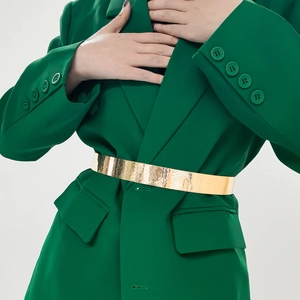 Detailed macro of golden metal belt with embossed floral patterns on green blazer