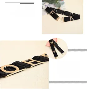 Detail of black elastic belt featuring a polished gold-tone metal fashion letter buckle