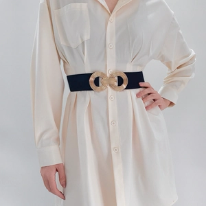 Close-up of golden geometric double ring buckle on a black elastic waist belt for women