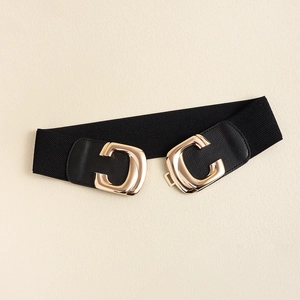 Close-up of golden double C buckle on black elastic waist belt for dresses and suits