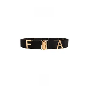 Close-up of black elastic belt featuring a gold buckle with amber gemstone and letters