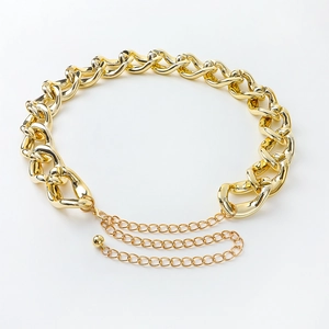Detail of chunky gold chain belt featuring large hollow links and a round ball pendant