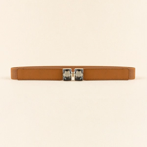 Détail d'une ceinture élastique marron fine avec une boucle en strass gris foncé