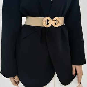 Detail of a beige elastic waist belt featuring a geometric gold metal buckle on a black suit