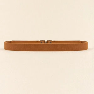 Détail de la ceinture élastique marron avec boucle en bronze vintage et finitions en cuir