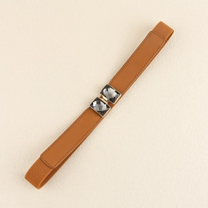 Détails d'une ceinture élastique marron avec boucle dorée ornée de strass gris foncé