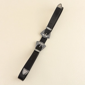 Détail d'une ceinture en cuir noir vintage avec double boucle en métal gravé