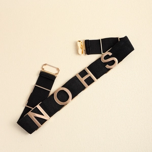 Detail of black elastic belt featuring golden NOHS metal letters and a secure clasp buckle