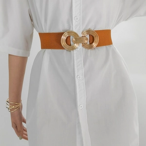 Detail of camel elastic waist belt with gold double-ring buckle on a white dress