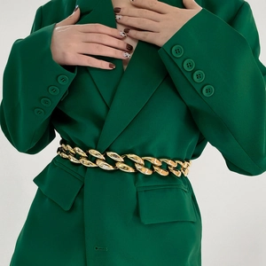 Detail shot of a chunky gold hollow chain belt styled over a dark green blazer jacket