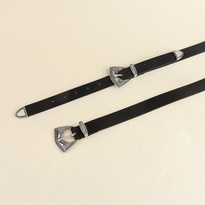 Détail d'une ceinture noire vintage avec boucles argentées gravées et embouts métal