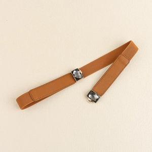 Détail d'une ceinture élastique marron avec boucles carrées serties de gemmes et cuir